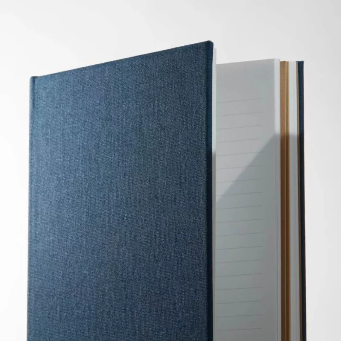 Midnight Blue Hardcover Notebook. Side shot of the cloth midnight blue notebook, showing lined pages.