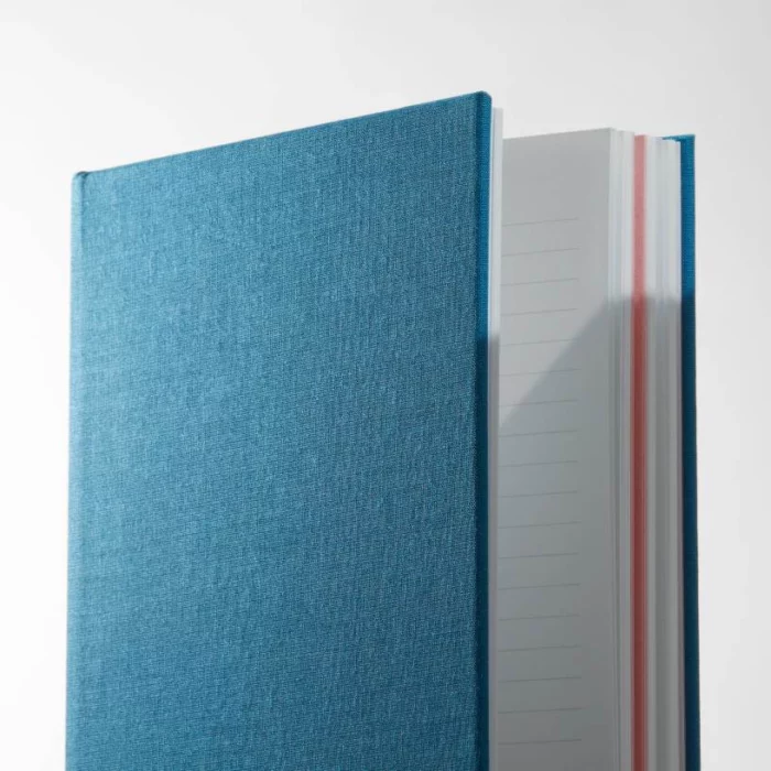 Sky Blue Hardcover Notebook. Lined. Side shot of the cloth sky blue notebook, showing lined pages.