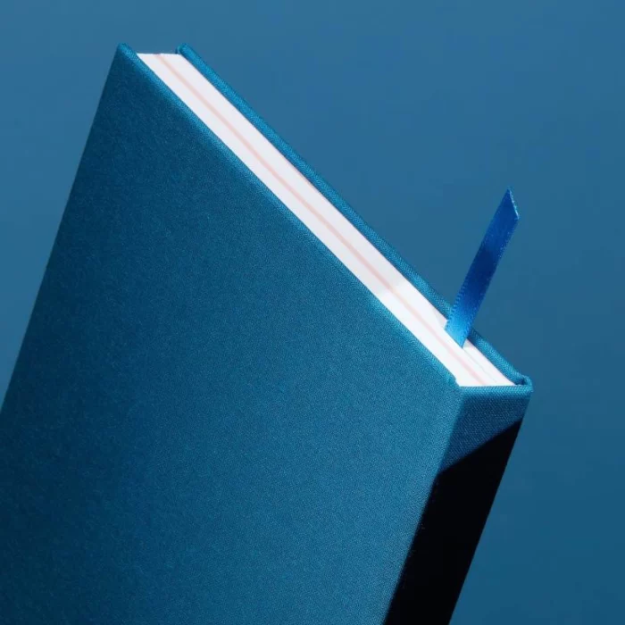 Sky Blue Hardcover Notebook. Ribbon. Side shot of the sky blue notebook, with the placeholder ribbon in sky blue.